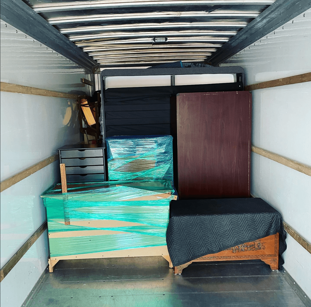 Moving truck loaded with wrapped furniture and large household pieces.